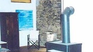 Una habitación con pared de piedra, chimenea, suelo de madera y vistas al exterior.