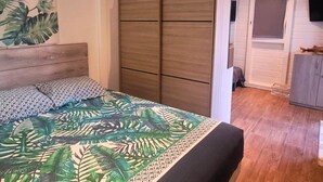 Un dormitorio con cama, armario, televisor y una puerta que da a otra habitación.