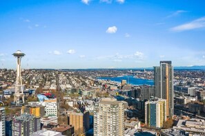 A cityscape with a prominent tower and high-rise buildings, indicating a densely populated urban area. - Corner Unit in the middle of it all - 99 Walkscore! (Seattle)