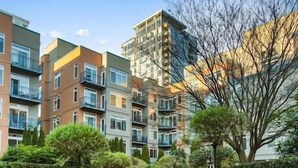 Ett bostadskomplex bestående av flera hyreshus, en central, asfalterad gångväg och anlagda områden med träd och buskar.