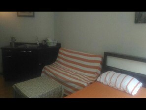 Cozy retreat with a single bed, ottoman, and dresser.