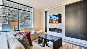 Un salon moderne avec un canapé, des fauteuils, une table basse, un téléviseur et une cheminée.