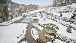 Un espace extérieur enneigé comprenant une piscine, un jacuzzi et des chaises longues.