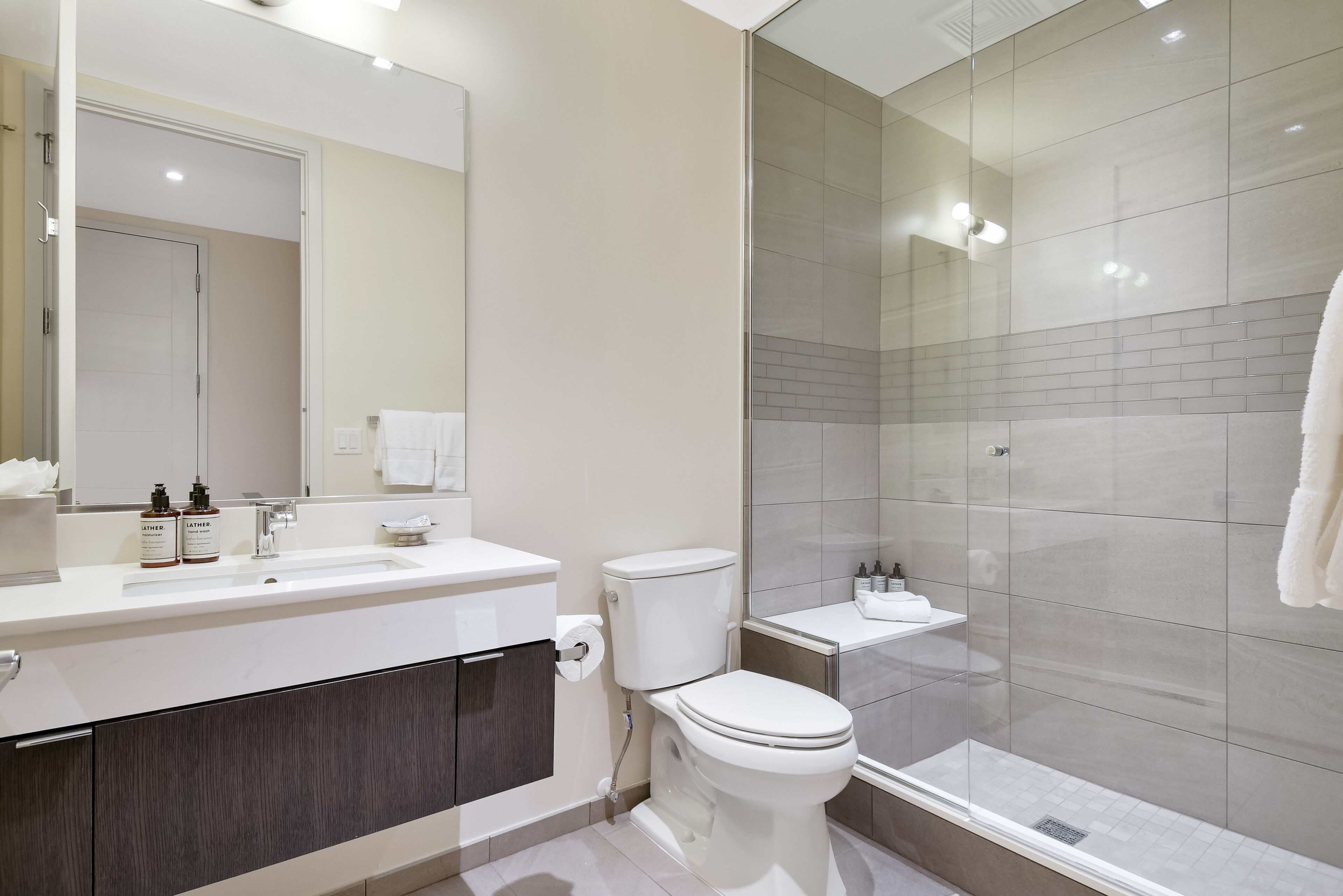 A modern bathroom with a glass shower enclosure, a white toilet, and a vanity with a mirror.