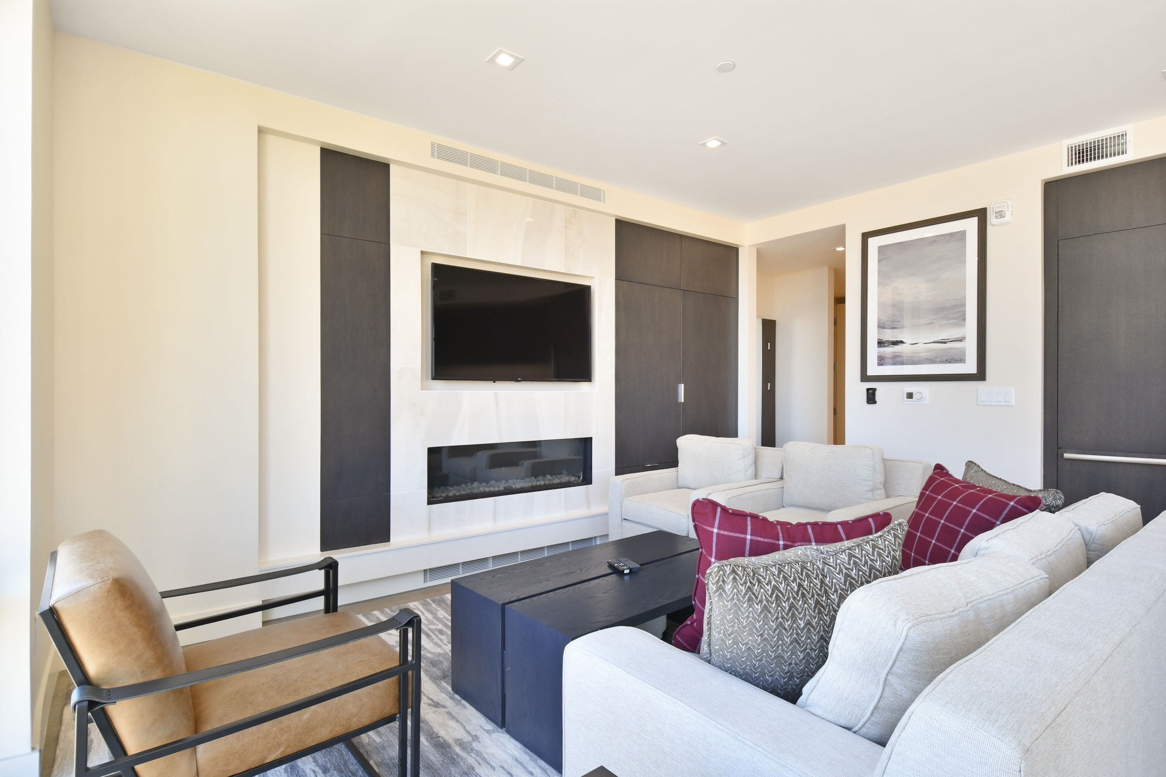 Una sala de estar moderna con un televisor de pantalla plana grande, una chimenea, un conjunto de sofás y una mesa de centro.