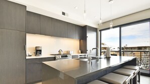 A modern kitchen with a large island, stainless steel appliances, and a view of the city. - New 1 BR Residence in Canyons Village- Ski in/out by RedAwning (Park City)