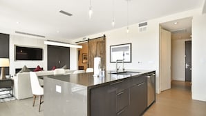 A modern kitchen with a large island, built-in appliances, and a dining area with a sofa and chairs. - New 1 BR Residence in Canyons Village- Ski in/out by RedAwning (Park City)