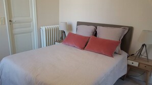 Ein Schlafzimmer mit Bett, zwei Kissen, einem Nachttisch, einer Lampe und einer Heizung.