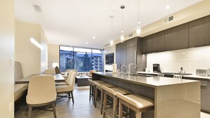 A modern kitchen with a large island, bar stools, and a dining area with a table and chairs. - Ski in/out Modern 2BR Residence in Canyons Village by RedAwning (Park City)