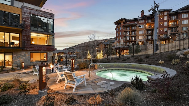 A modern hotel with a heated outdoor pool, stone patio, and lounge chairs. - Ski in/out Modern 2BR Residence in Canyons Village by RedAwning (Park City)