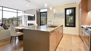 A modern kitchen with a large island, built-in appliances, and large windows offering views of the surrounding area.