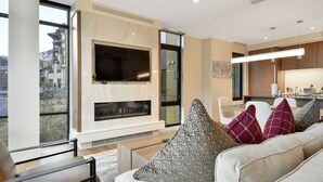 A modern living room with a fireplace, large windows, and a view of a mountain.