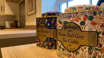 Tre contenitori per tè su un tavolo di legno, decorati con motivi floreali ed etichette che indicano tè Earl Grey.