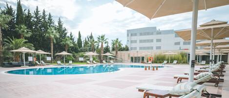 A poolside area with lounge chairs, umbrellas, and a building in the background.