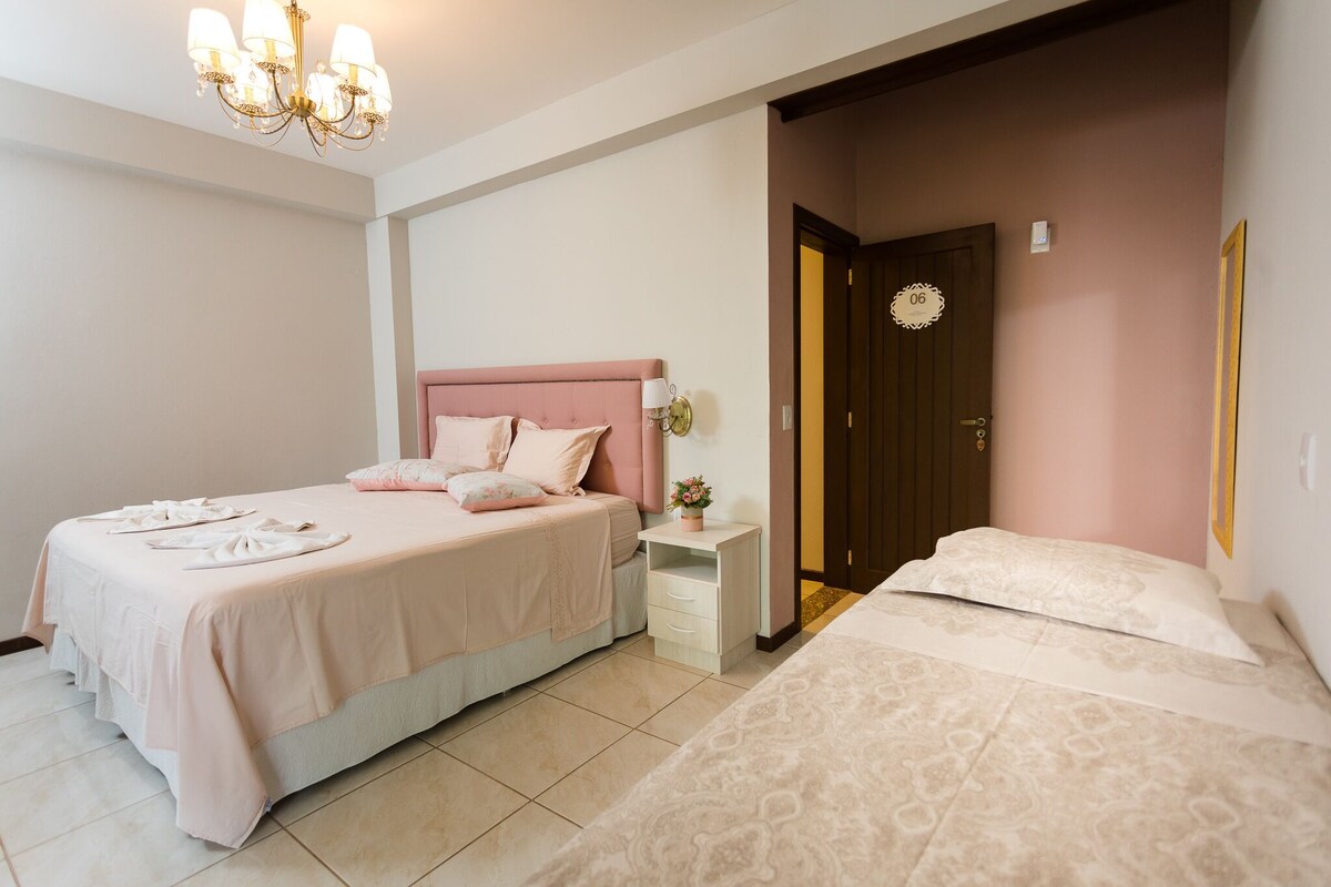 Un dormitorio con cama doble, mesita de noche, lámpara de noche y candelabro, con una puerta numerada.