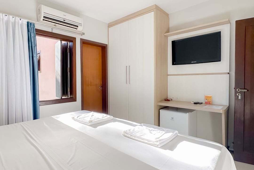 Una habitación de hotel con una cama, un escritorio, un televisor y un equipo de aire acondicionado.