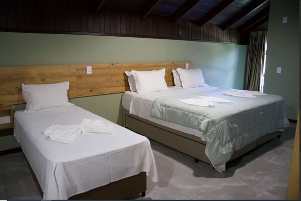 Une chambre avec deux lits simples, chacun doté d’une tête de lit en bois et de draps blancs.