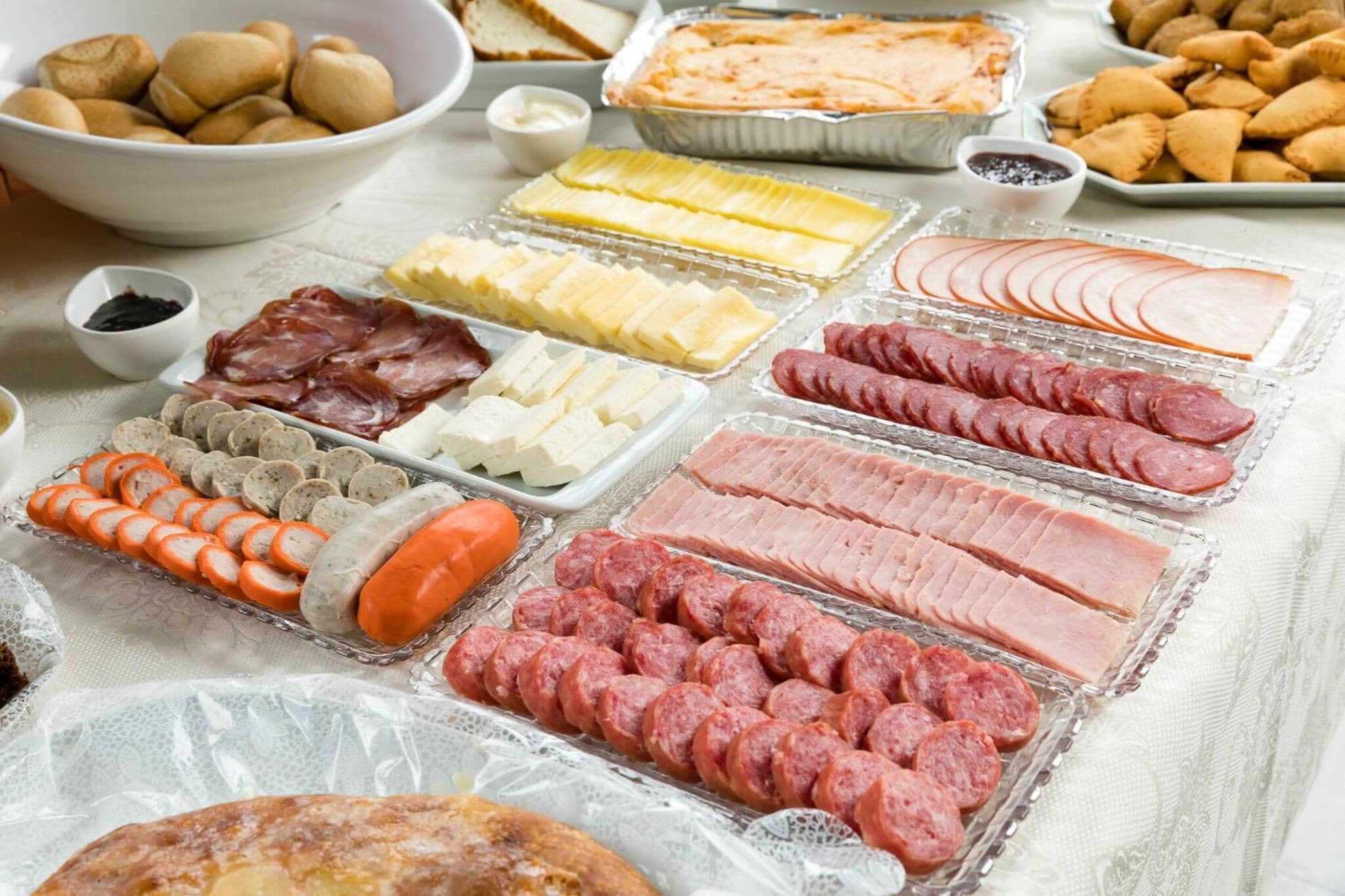 A variety of food items including sliced meats, cheeses, and pastries arranged on a table.