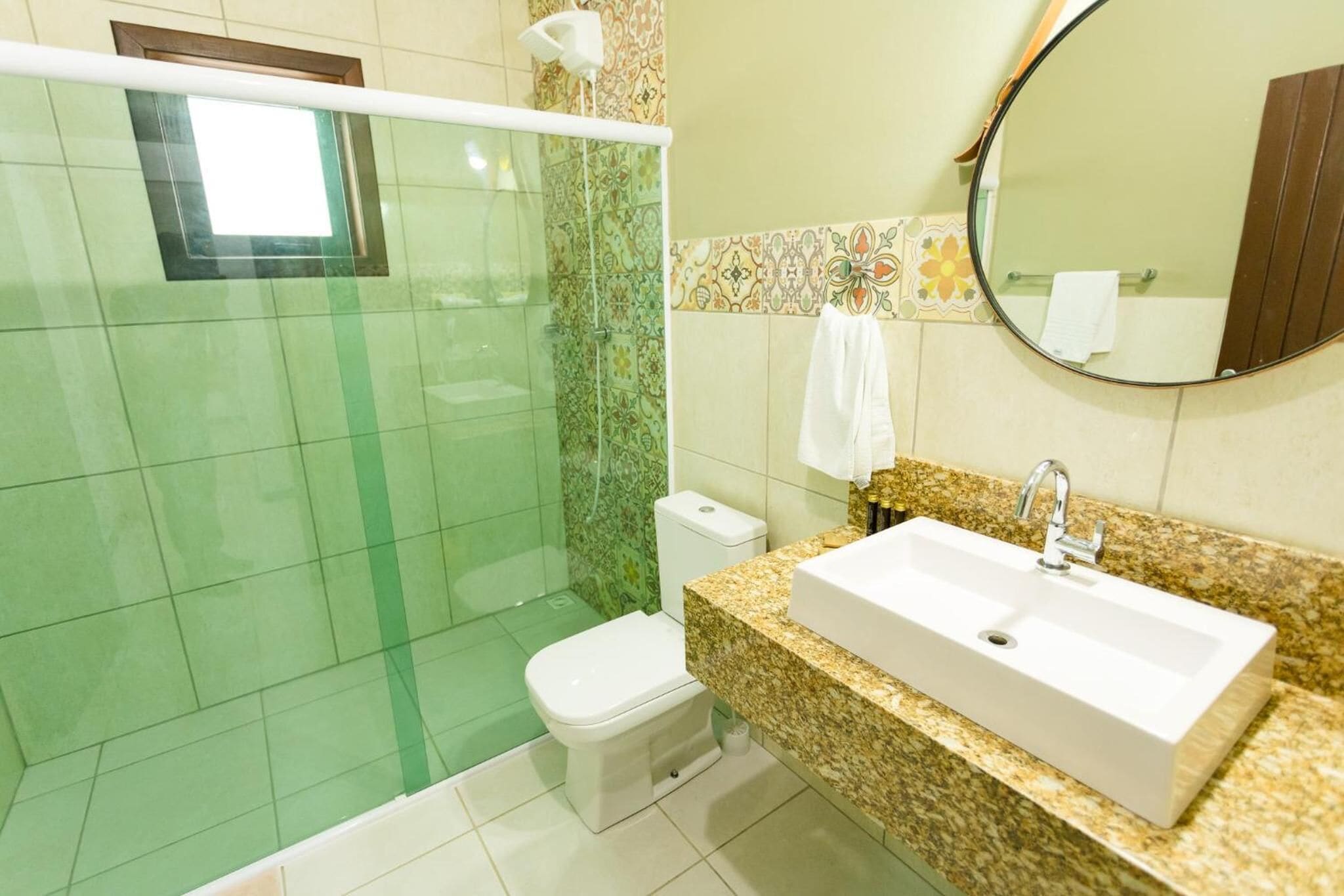 Un baño con ducha, inodoro, lavamanos y espejo.