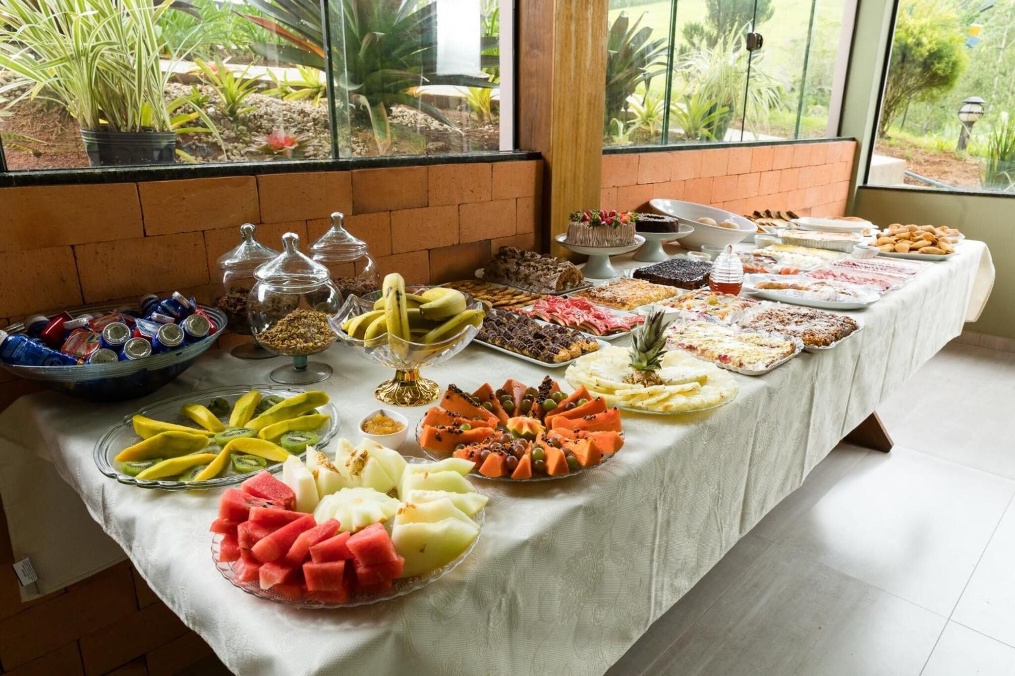 Een buffet met diverse soorten fruit, desserts en drankjes.