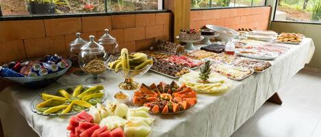Una mesa de buffet con una variedad de frutas, postres y bebidas.