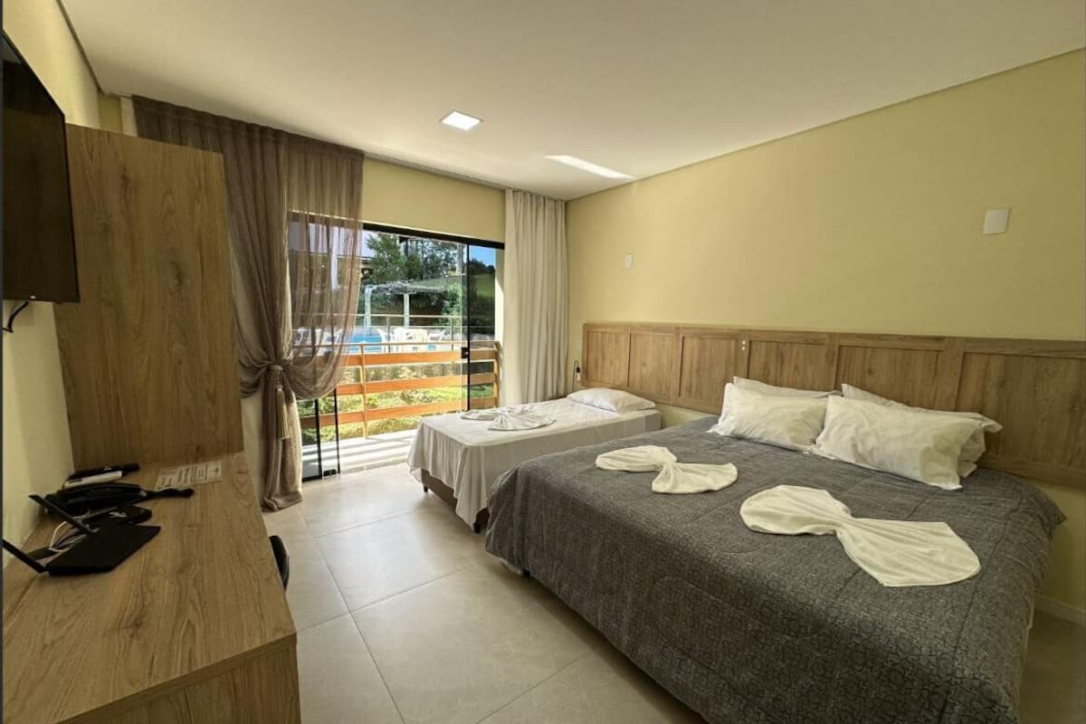 A hotel room with a bed, a desk, and a view of a pool area.