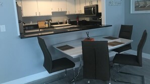 A modern kitchen with white cabinets, a black countertop, and a dining area with a table and chairs.