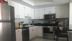 A kitchen with white cabinets, stainless steel appliances, and a black countertop.