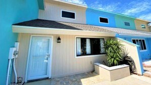 A two-story building with a light blue exterior, a white door, and a small window above the door.