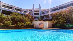 A swimming pool with a modern building in the background. - 2 ROOMS+CABIN-AIR CONDITIONING- SWIMMING POOL- SOUTH-FACING TERRACE- LOVELY LAKE VIEW, WIFI. (La Grande-Motte)