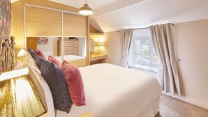 Un dormitorio con una cama grande, un armario, un escritorio y un ventanal con cortinas.