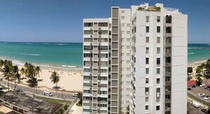 A beachfront hotel with multiple floors, a beach view, and a clear sky. - Flamenco Beach 2BDR Oceanfront Pool Parking (Isla Verde)
