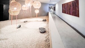 Un couloir doté d’un sol en galets, de luminaires sphériques suspendus et d’un grand panneau en bois sur le mur.