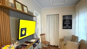 A cozy living room with a television, a wooden chair, a sofa, and a motivational poster on the wall. - Pousada Bello  Outono (Canela)