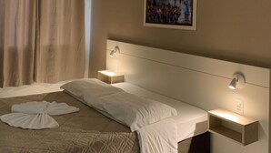 A hotel room with a bed, two bedside tables, a wall-mounted light, a painting, and a window with curtains. - Pousada Bello  Outono (Canela)