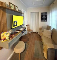En stue med tv, bogreol, sofa, lænestol og et tæppe.