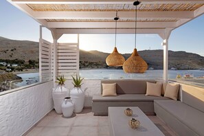 Un balcone con una divano, due grandi vasi bianchi e lampade in vimini appese.