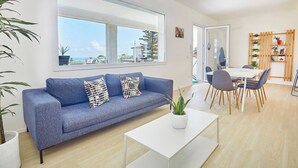 A modern living room with a blue sofa, white coffee table, and a dining area with a white table and chairs. - VILLA CIURIDDA (Alcamo)
