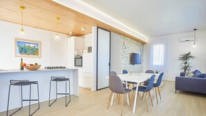 A modern kitchen with a dining area, wooden ceiling, and a stone wall. - VILLA CIURIDDA (Alcamo)