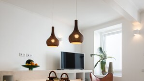 Una cocina moderna con una isla central, luces colgantes, un televisor de pantalla plana y una planta en maceta.