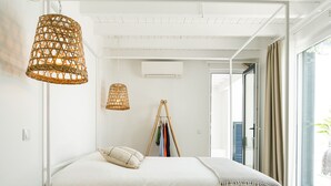 Un dormitorio moderno con cama, una mesita de madera, un tapete tejido y una lámpara colgante.