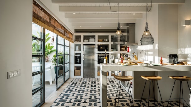 Cocina moderna con piso estampado, electrodomésticos integrados y una barra con taburetes.