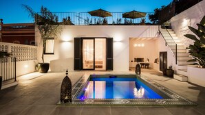 Un área de piscina moderna con una piscina cristalina, una escalera y mobiliario exterior.