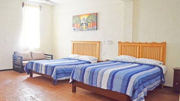 A room with two wooden beds, a small seating area, and a painting on the wall.