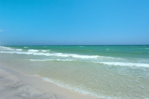 A beach with clear turquoise water and a sandy shore.
