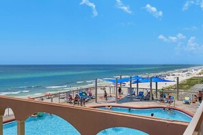 A pool area with a view of the beach and ocean.