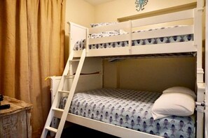 Una cama litera con escalera, un colchón estampado y una almohada.