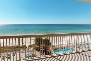 A balcony with a view of the beach and a pool.