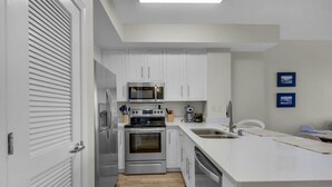 A modern kitchen with white cabinets, stainless steel appliances, and a large island with a sink.