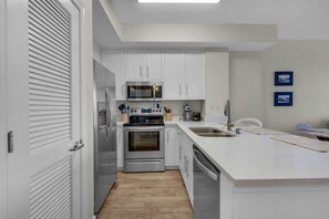 A modern kitchen with white cabinets, stainless steel appliances, and a large island with a sink.